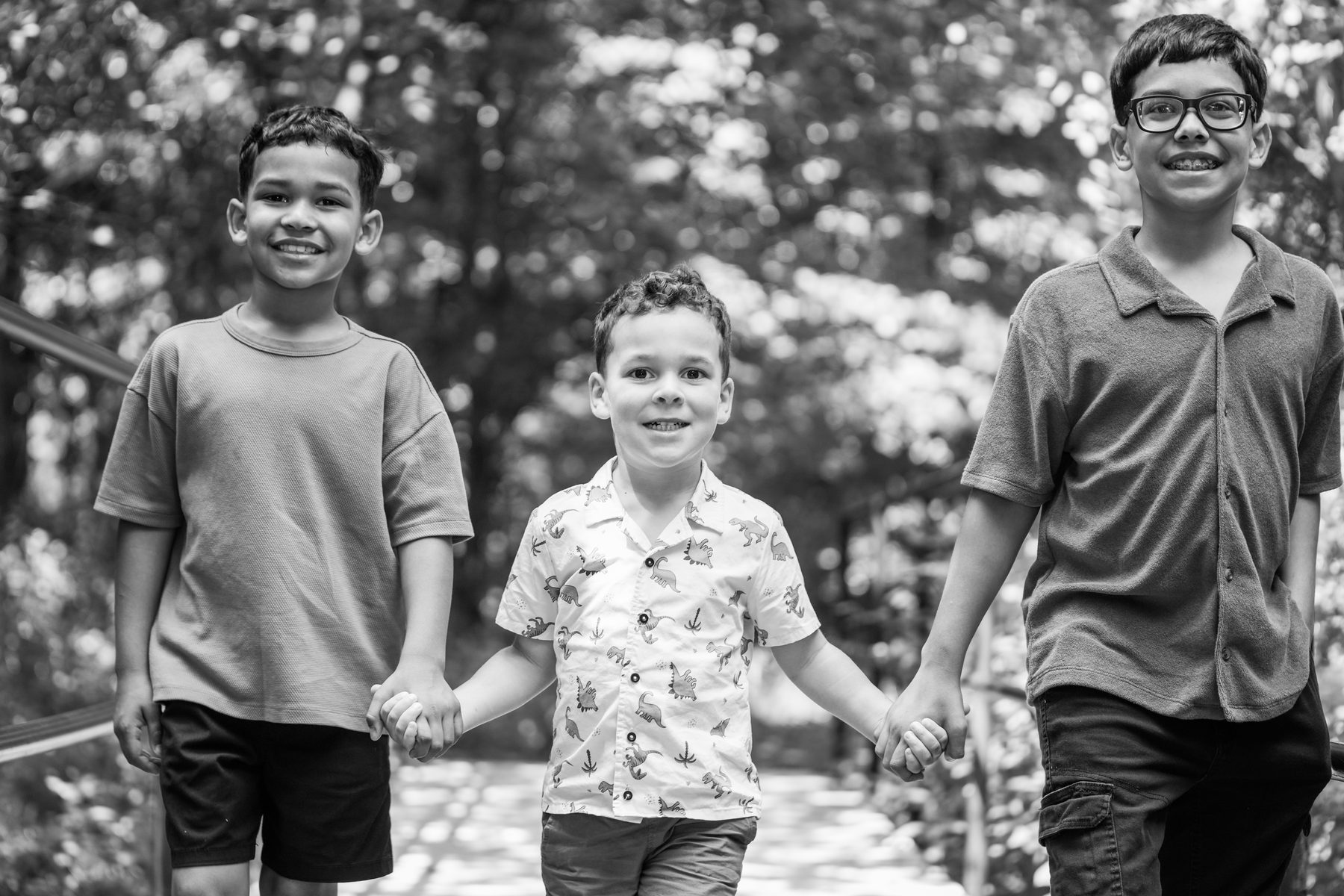 Black and white family portrait of three brothers walking and holding hands in Western Massachusetts